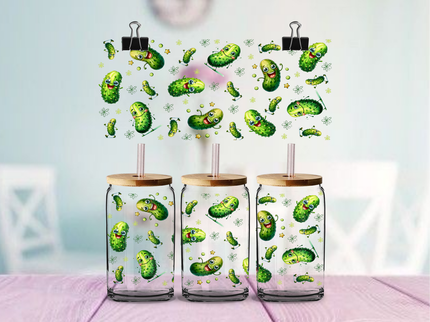 Three glass tumblers with wooden lids and pickle pattern on a light background