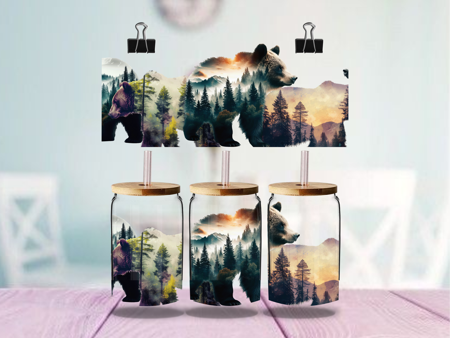 Three glass jars with wooden lids featuring bear and nature designs, held up by clips against a light background.